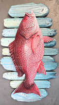 A hand-carved Red Snapper fish wall sculpture mounted on a rustic, weathered blue and green wooden plank background. Handmade, one-of-a-kind up-cycled Eco-Art from locally reclaimed materials by Thomas Walsh at FWB Artists.